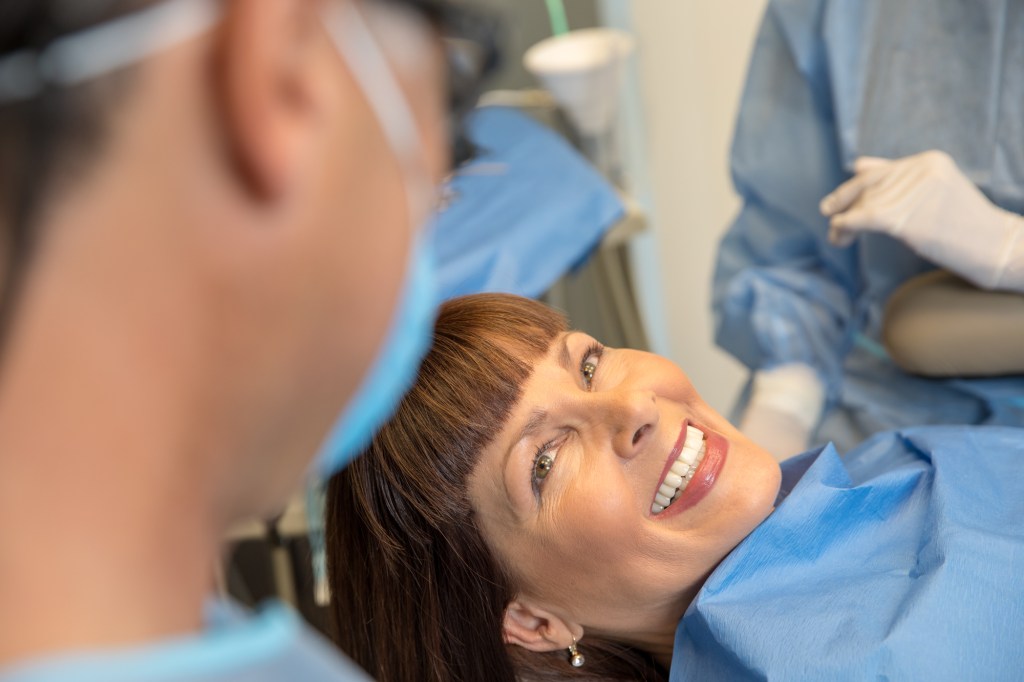 a smiling lady showing her teeth after a periodontal service