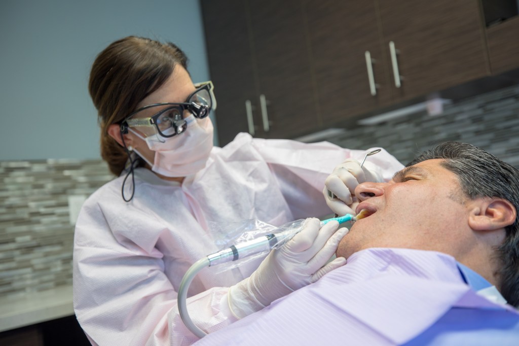 a dentist performing a periodontal service to a patient