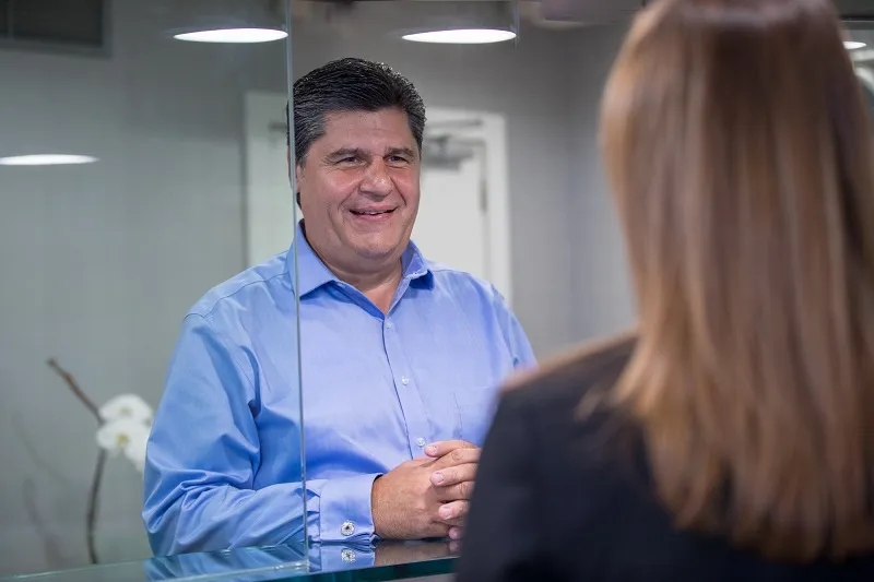 Male patient in blue shirt having consultation with female staff member at reception area