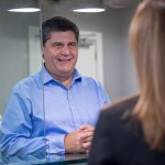 Male patient in blue shirt having consultation with female staff member at reception area