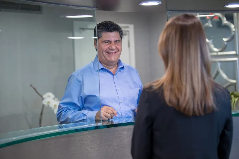 Male patient at reception desk speaking with female receptionist in professional office setting
