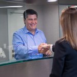 Male patient shaking hands with receptionist at front desk, demonstrating friendly customer service